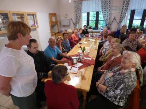 Seniorzy biesiadują przy stole w czasie Spotkania integracyjnego w Caritas Zakrzów.