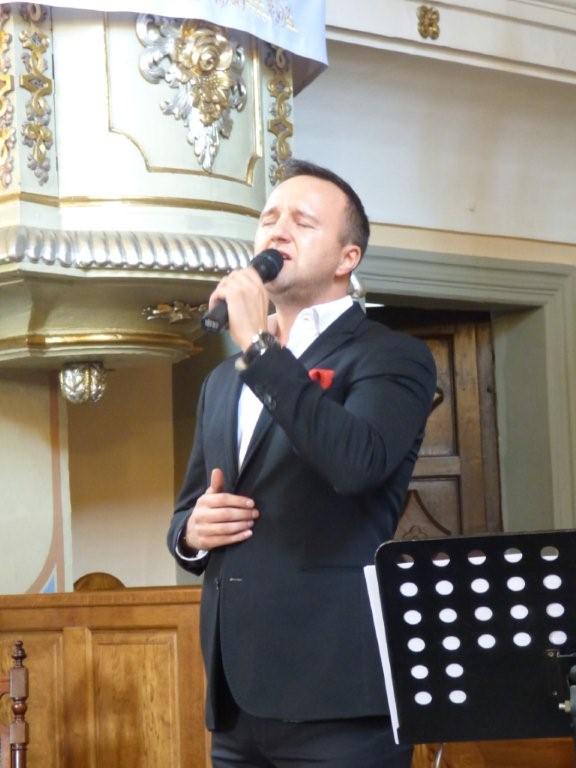Mateusz Mijal śpiewa stojąc z mikrofonem w ręce.