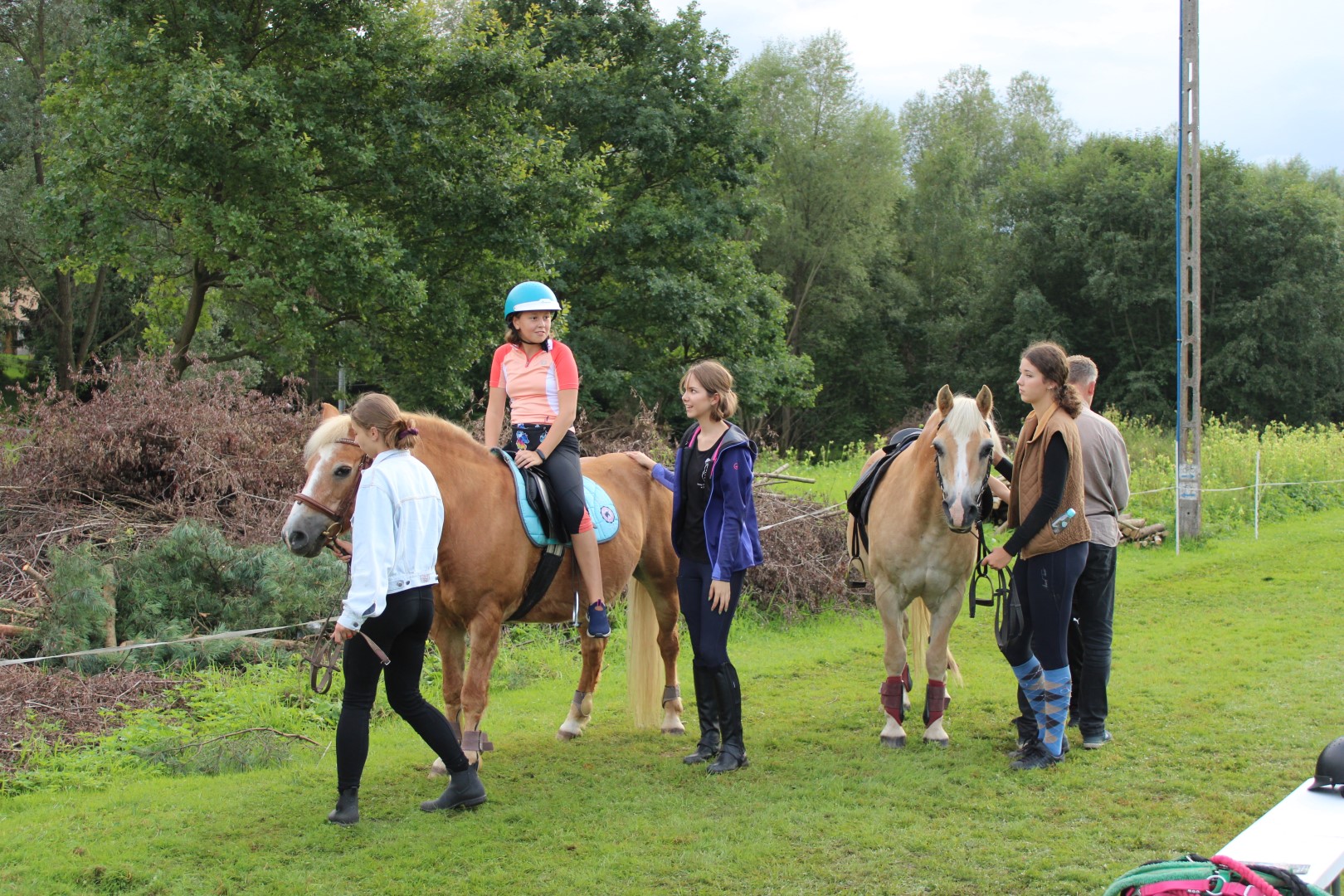 Na zdjęciu znajdują się instruktorzy prowadzący konie, na których znajdują się dzieci.