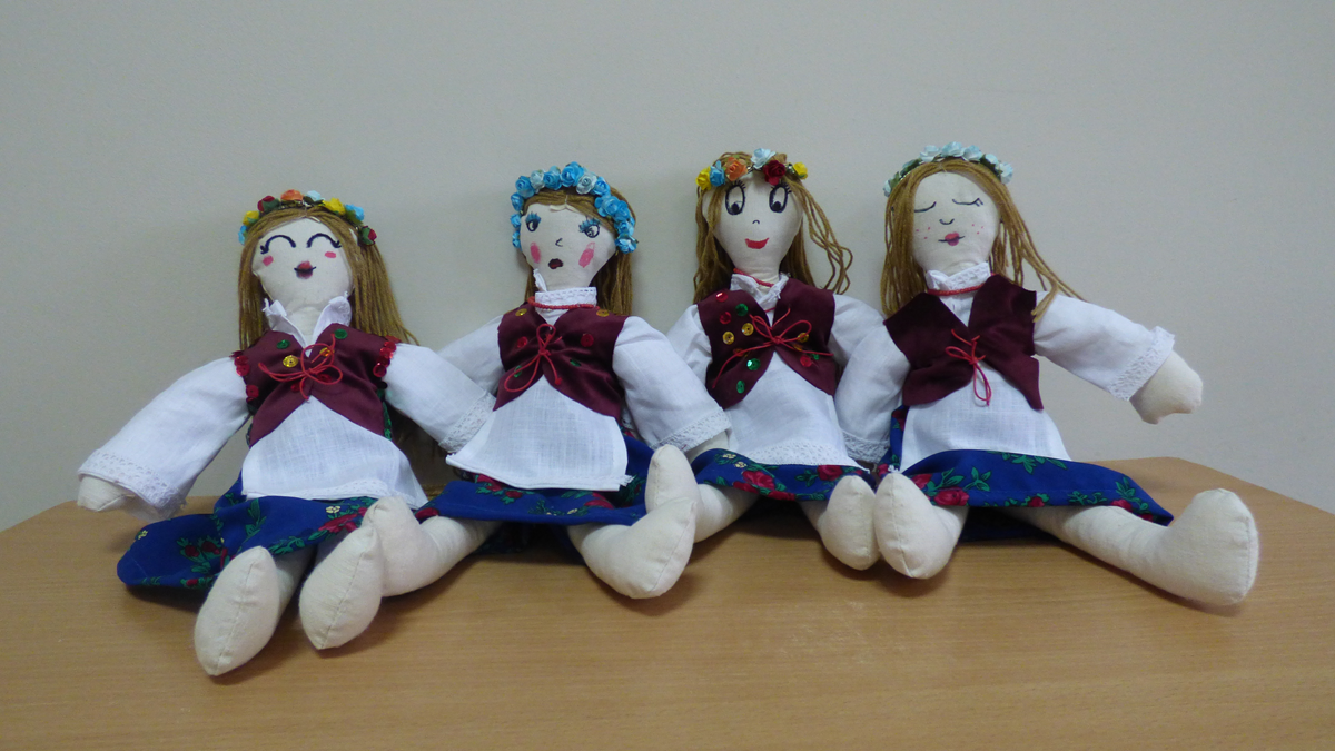 Cztery lale siedzą na stole ubrane w strój ludowy.