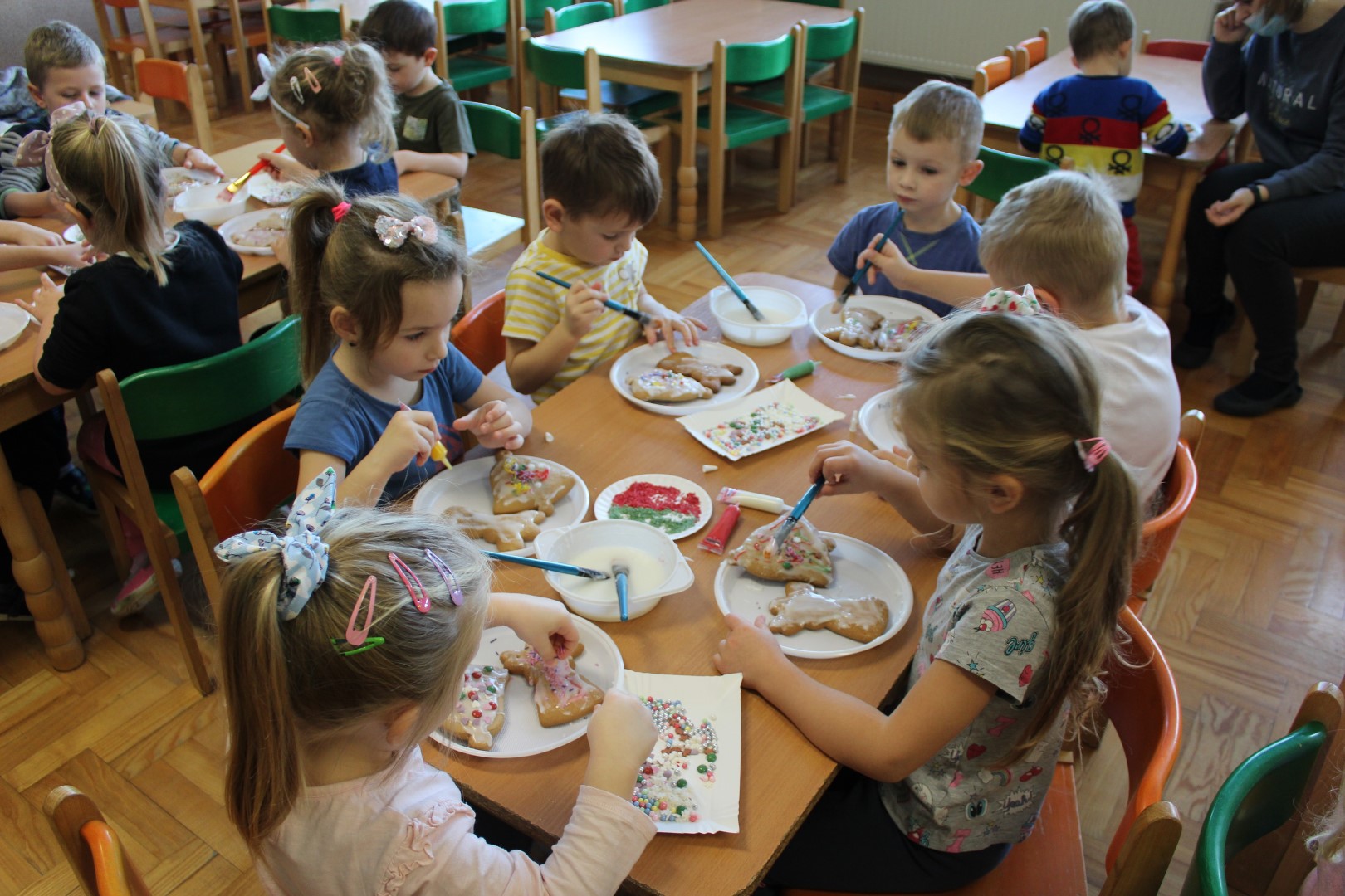 Sześcioro przedszkolaków ze Stronia siedzi przy stoliku i dekoruje pierniczki.