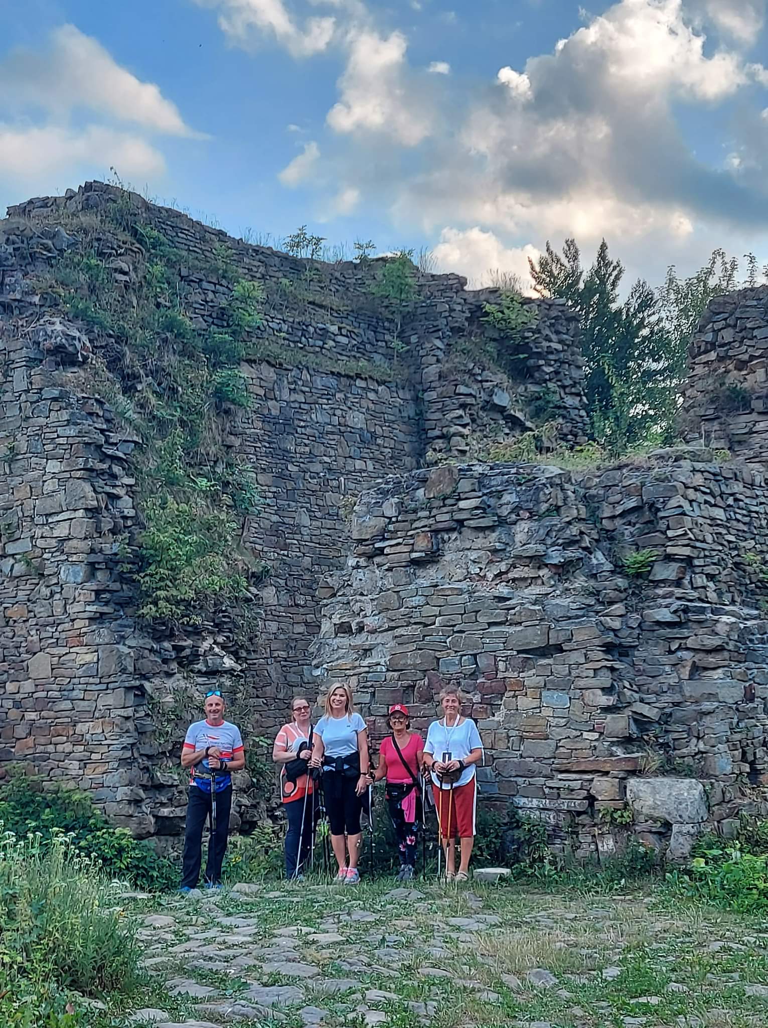Cztery kobiety i jeden mężczyzna stoją przed ruinami zamku w Lanckoronie i pozują do zdjęcia.