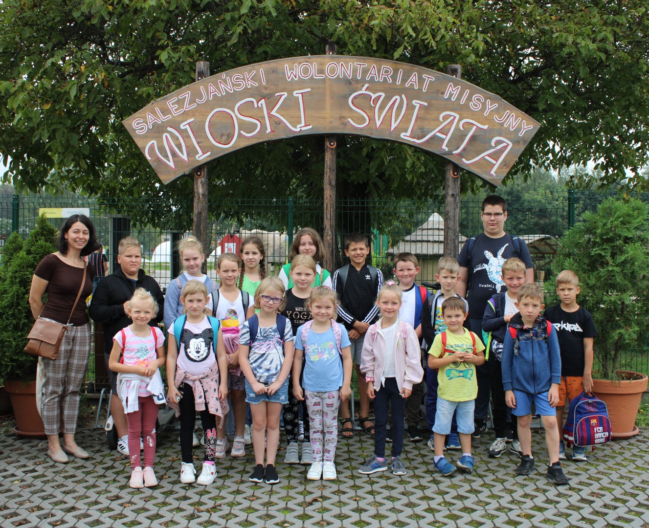 Mieszana grupa dwudziestu osób pozuje do zdjęcia grupowego na wakacyjnej wycieczce do Krakowa pod szyldem Wioski Świata.
