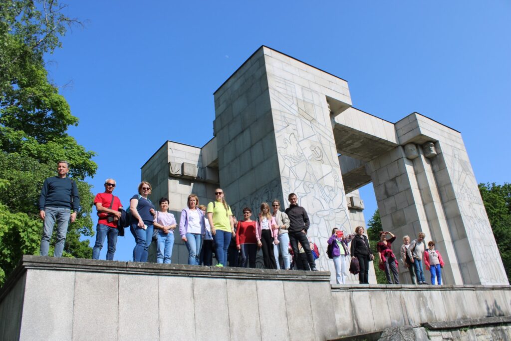 Uczestnicy wycieczki stoją przed Pomnikiem Czynu Powstańczego.