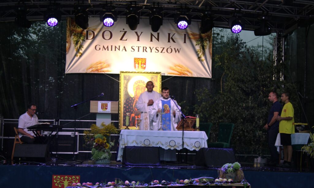 Zdjęcie przedstawia ołtarz polowy, na którym ksiądz odprawia uroczystą Mszę św. dożynkową.