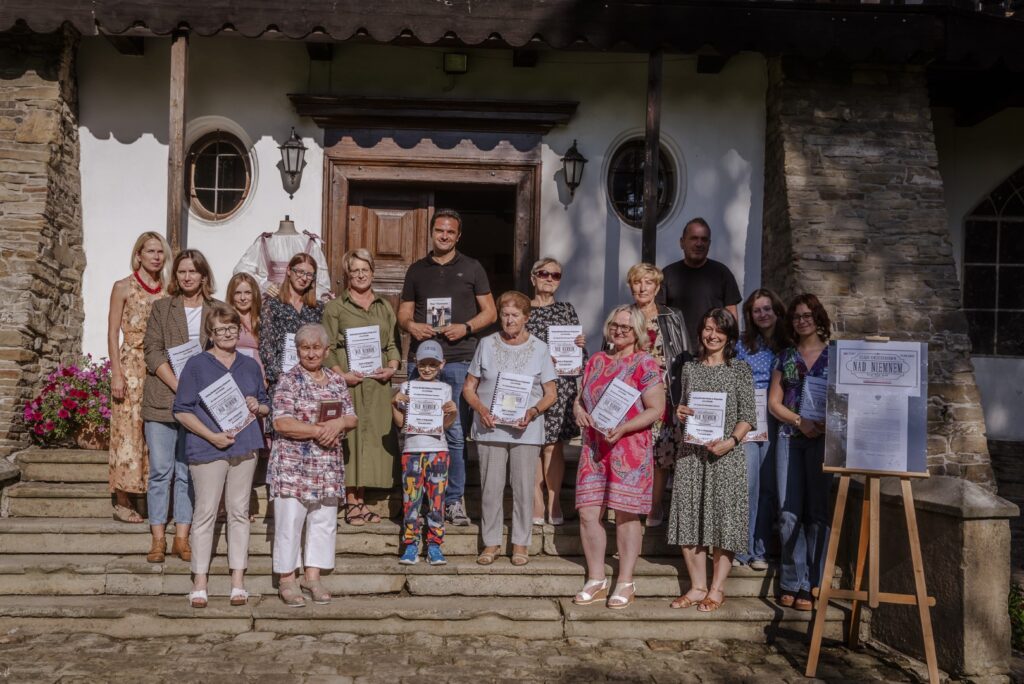 zdjęcie zbiorowe uczestników Narodowego Czytania - na tle zabytkowego dworku stoją osoby z książkami w dłoniach